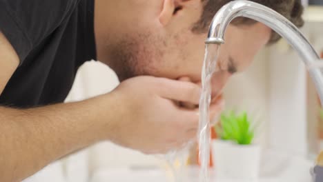 Young-man-washes-his-face-in-the-sink-with-cold-water.